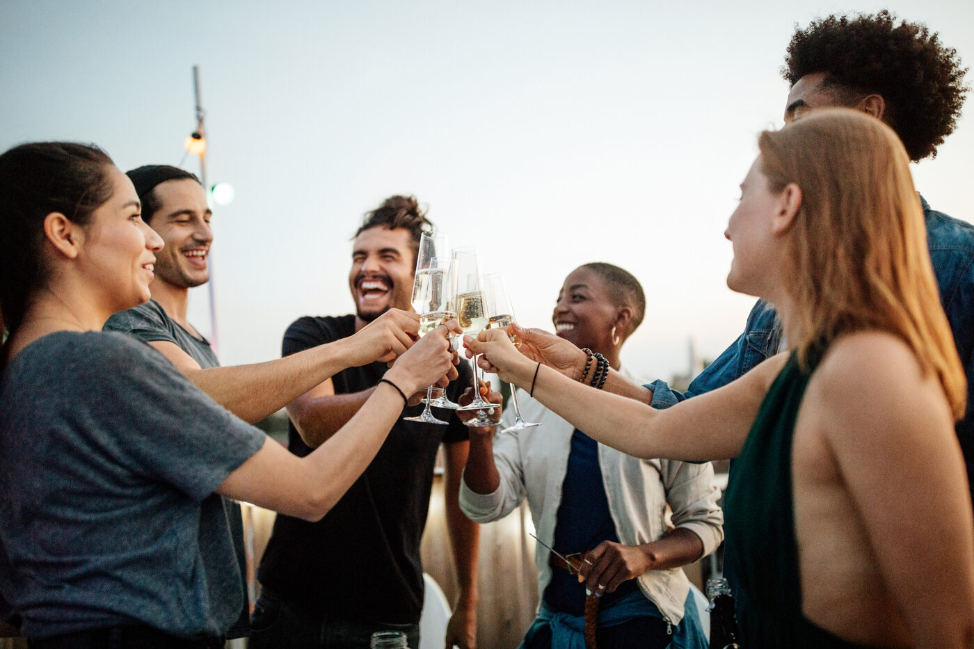 Gäste stoßen bei sommerlicher Abendstimmung gemeinsam an